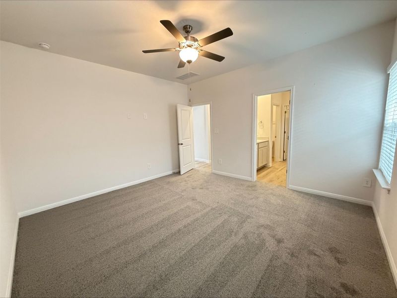 Unfurnished bedroom with light carpet, a ceiling fan, and connected bathroom