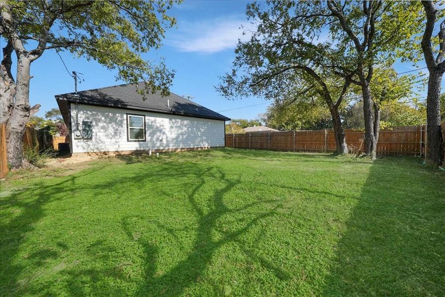 Rear view of house featuring a fenced backyard and a shingled roof