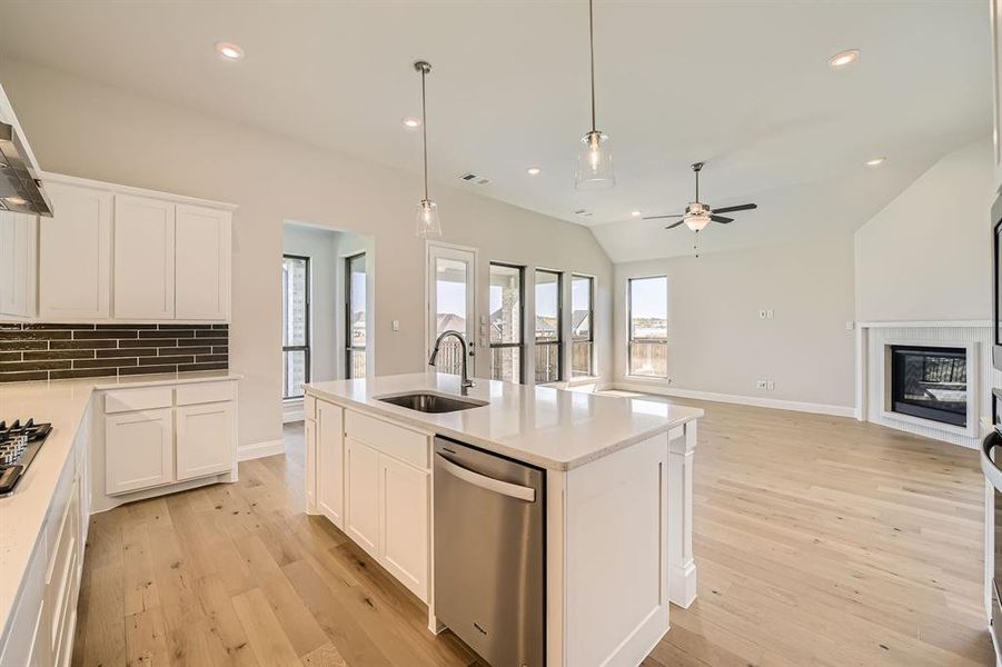 Kitchen featuring a kitchen island with sink, vaulted ceiling, sink, stainless steel appliances, and white cabinetry