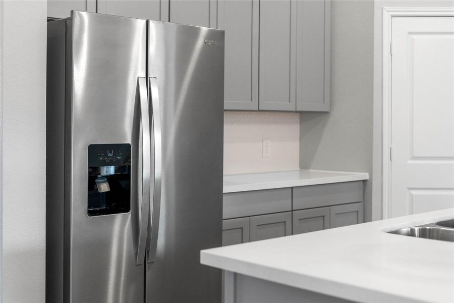 Kitchen comes equipped with a side-by-side Whirlpool refrigerator.