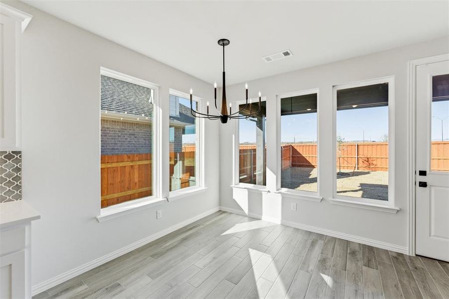Unfurnished dining area with a chandelier, wood finish floors, and healthy amount of natural light