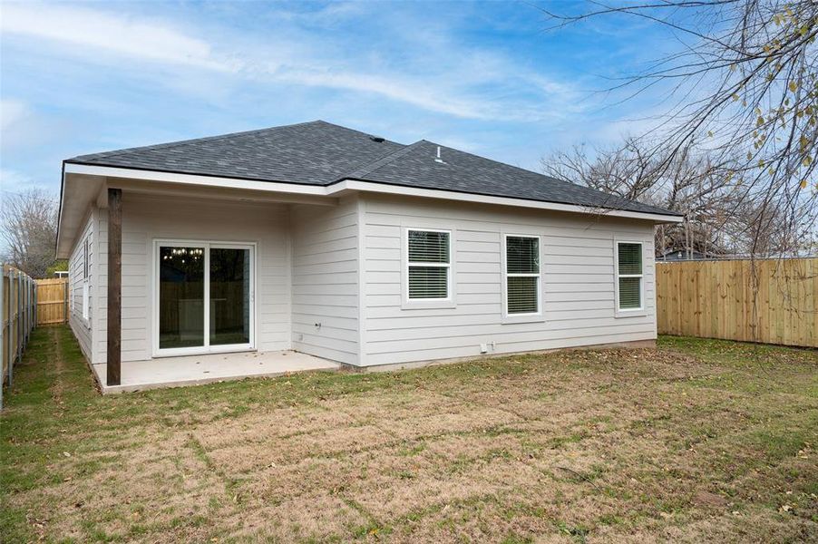 Rear view of property with a lawn and a patio area