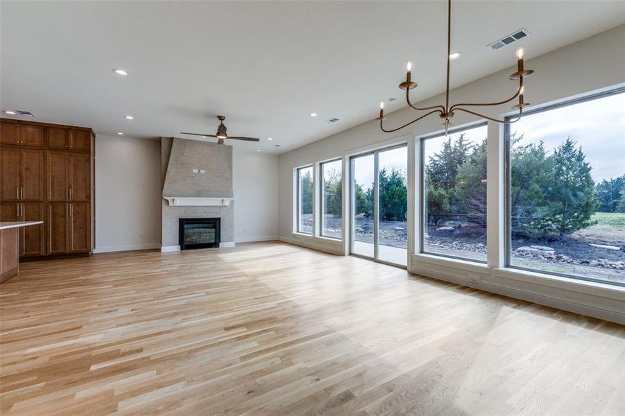 Unfurnished living room with light wood finished floors, a ceiling fan, recessed lighting, baseboards, and a fireplace