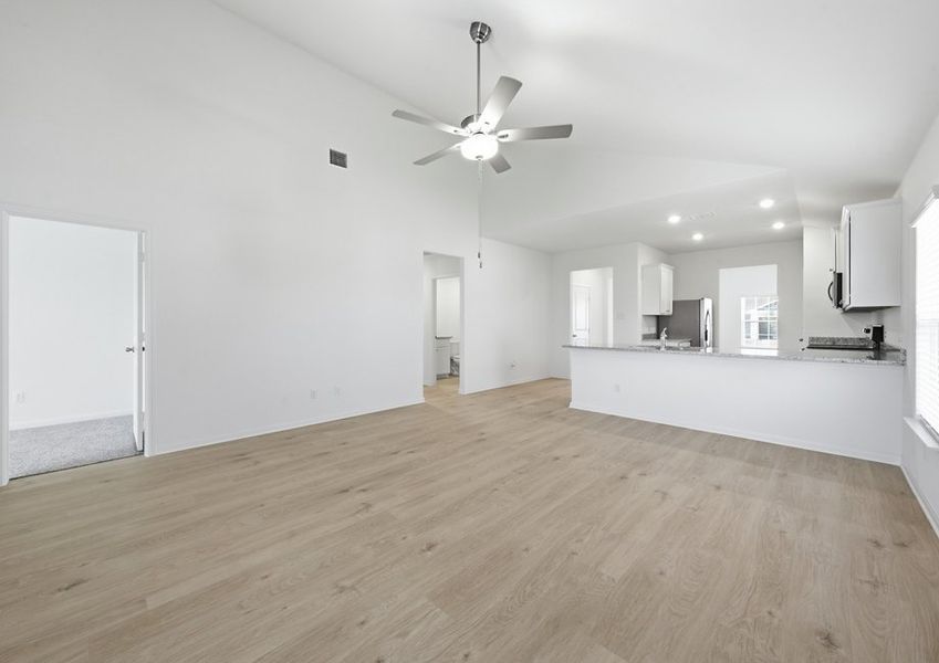 Family room featuring a ceiling fan and wood-look vinyl flooring open to the kitchen. Family room featuring a ceiling fan and wood-look vinyl flooring open to the kitchen.