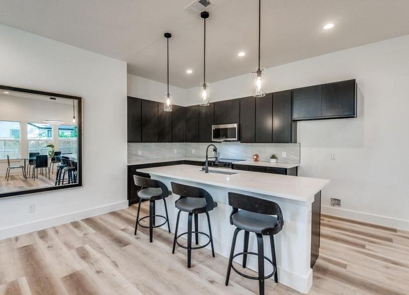 Kitchen with decorative light fixtures, backsplash, and light hardwood / wood-style flooring