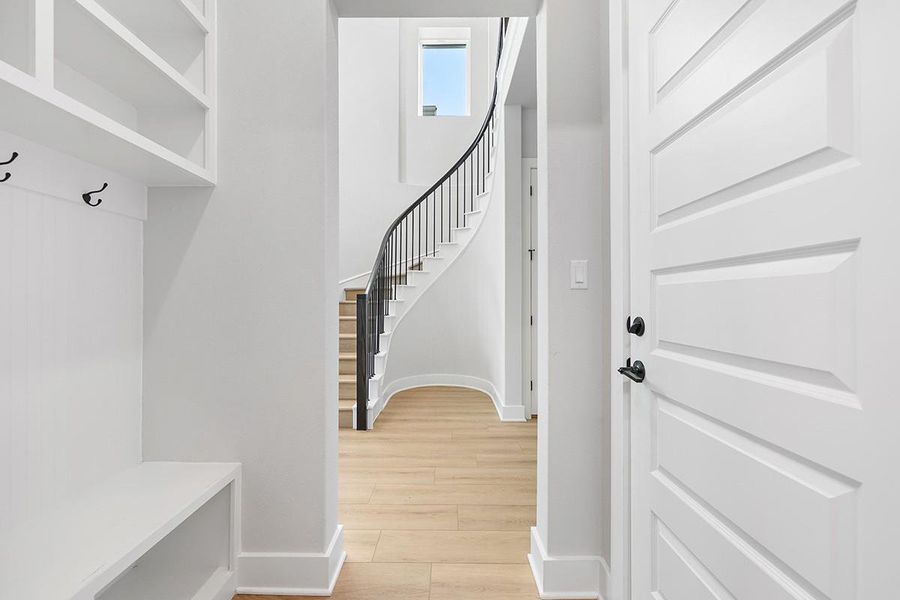 An elegant curved staircase with iron spindles anchors the bright entry hall.