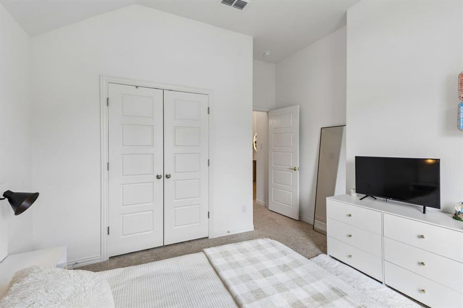 Interior bedroom featuring vaulted ceilings and neutral wall tones