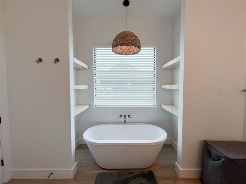 Full bath with a freestanding tub and light wood-type flooring