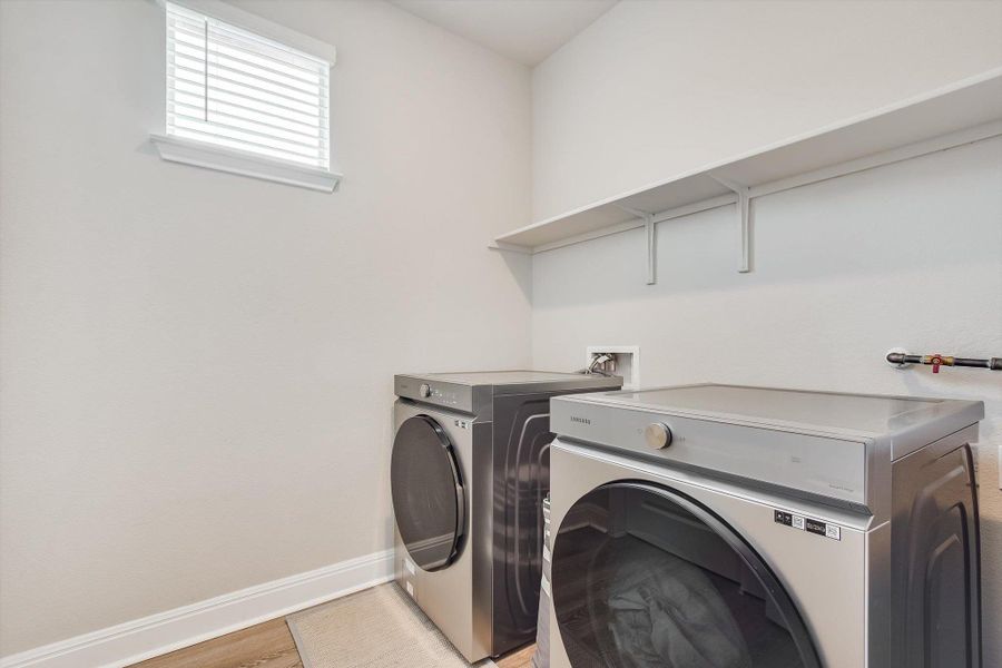 Washroom with laundry area, light wood-style flooring, baseboards, and separate washer and dryer