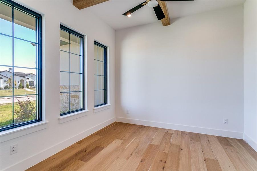 Unfurnished room featuring beam ceiling, light wood-type flooring, and a ceiling fan