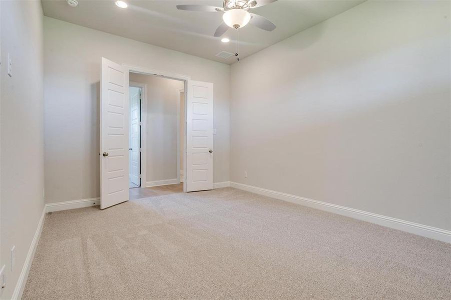 Unfurnished bedroom with ceiling fan and light carpet