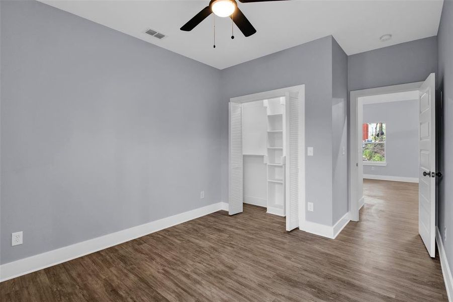 Unfurnished bedroom featuring dark wood-style flooring, a closet, and ceiling fan