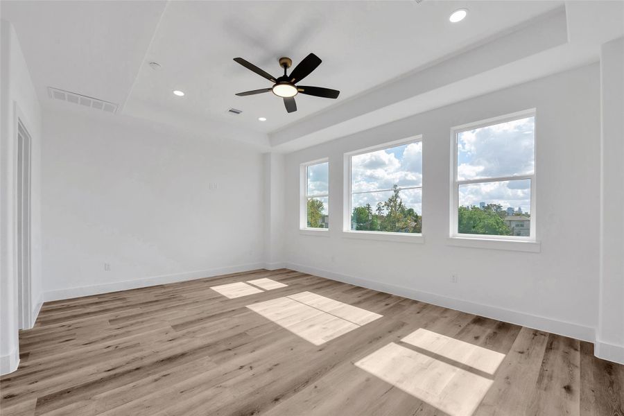 The wall of windows in the primary bedroom bring in lots of natural light. Each bedroom has a ceiling fan with light to help keep the home cool.