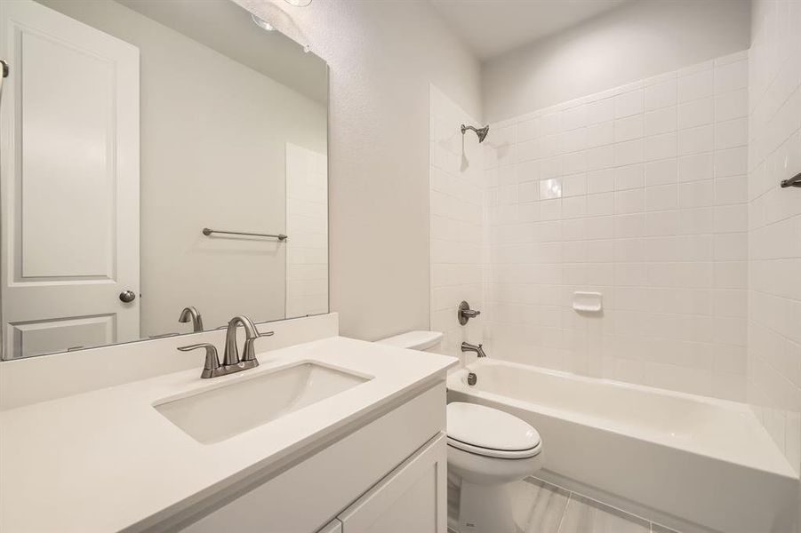 Full bathroom with vanity, tiled shower / bath combo, and toilet