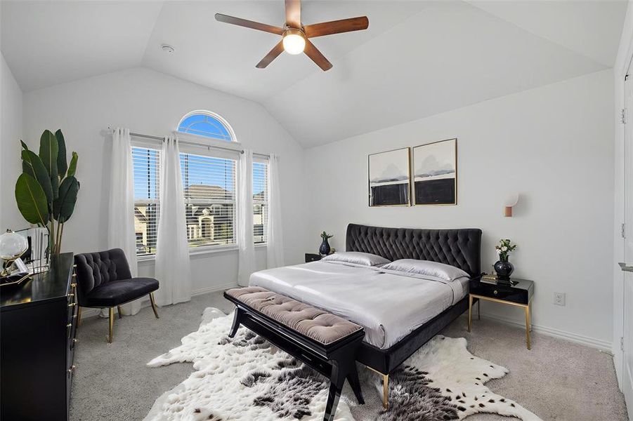 Bedroom featuring light colored carpet, lofted ceiling, and a ceiling fan Bedroom featuring light colored carpet, lofted ceiling, and a ceiling fan