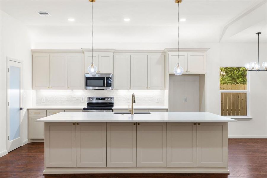 Kitchen featuring backsplash, dark hardwood / wood-style flooring, an island with sink, appliances with stainless steel finishes, and sink