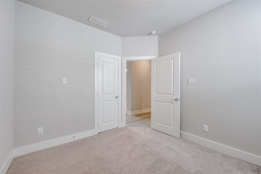 Unfurnished bedroom with light carpet and baseboards