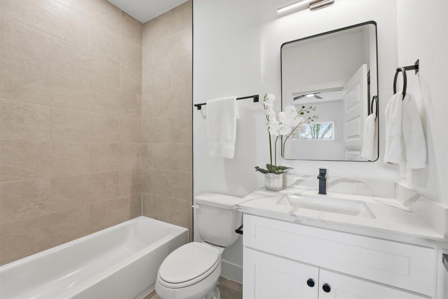 Modern bathroom featuring a tiled tub and shower combination, sleek white vanity with quartz countertop, contemporary fixtures, and a clean, bright design with timeless finishes.