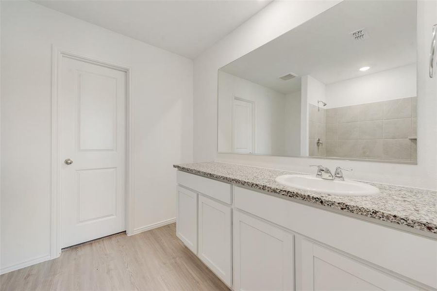 Bathroom with vanity, hardwood / wood-style floors, and tiled shower