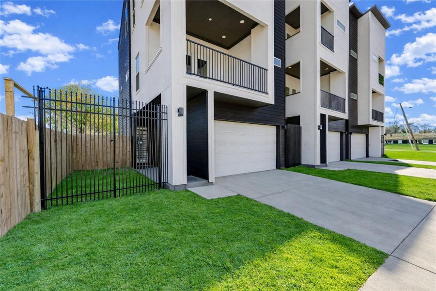 Modern multi-story home with a clean, contemporary design. It features spacious balconies, and a fenced yard. The exterior combines light and dark tones, offering a sleek and stylish appearance.