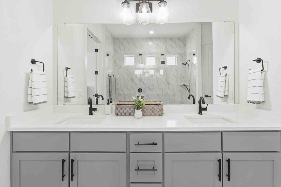 Dual vanity featuring light gray cabinetry with black hardware, white countertops, and integrated rectangular sinks