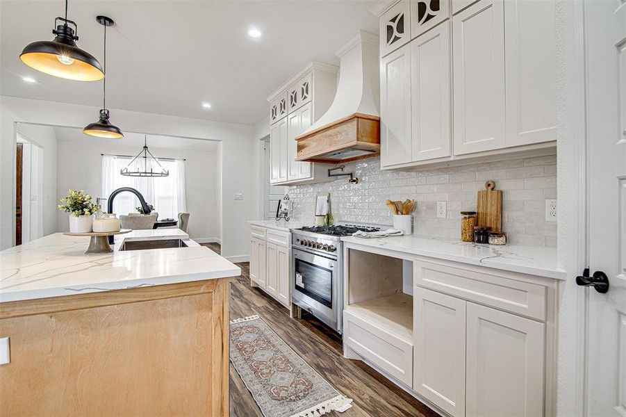 Kitchen featuring white cabinets, a center island with a farm sink, and custom range hood