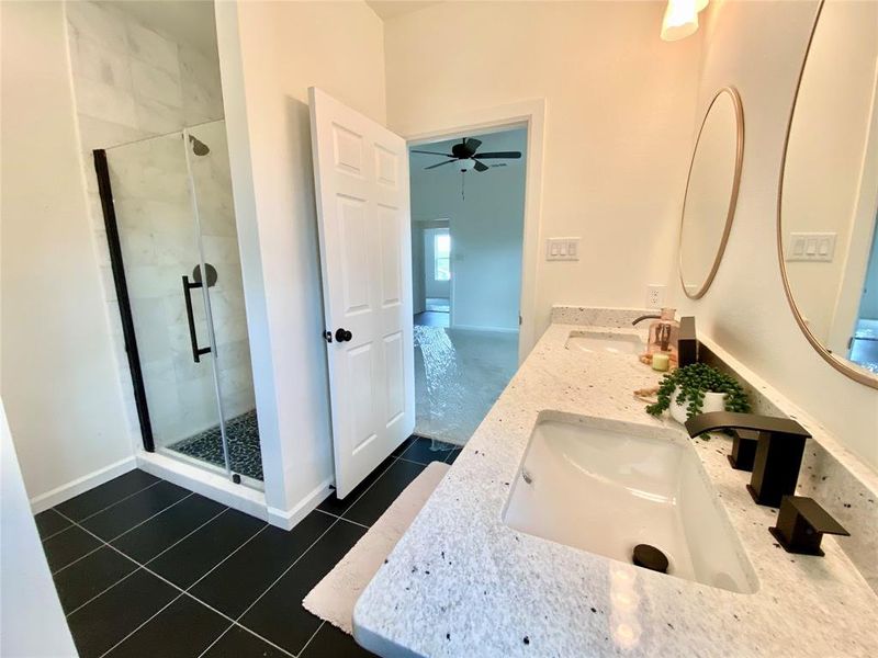 Bathroom featuring walk in shower, ceiling fan, tile patterned floors, and double sink vanity