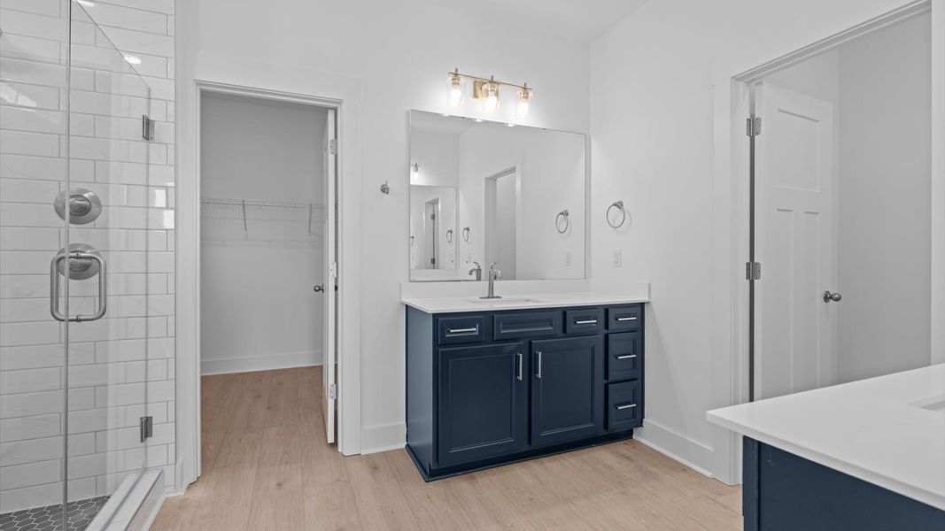 Elegant primary bathroom featuring a spacious tiled walk-in shower and two vanities in this first-class DRB Homes design