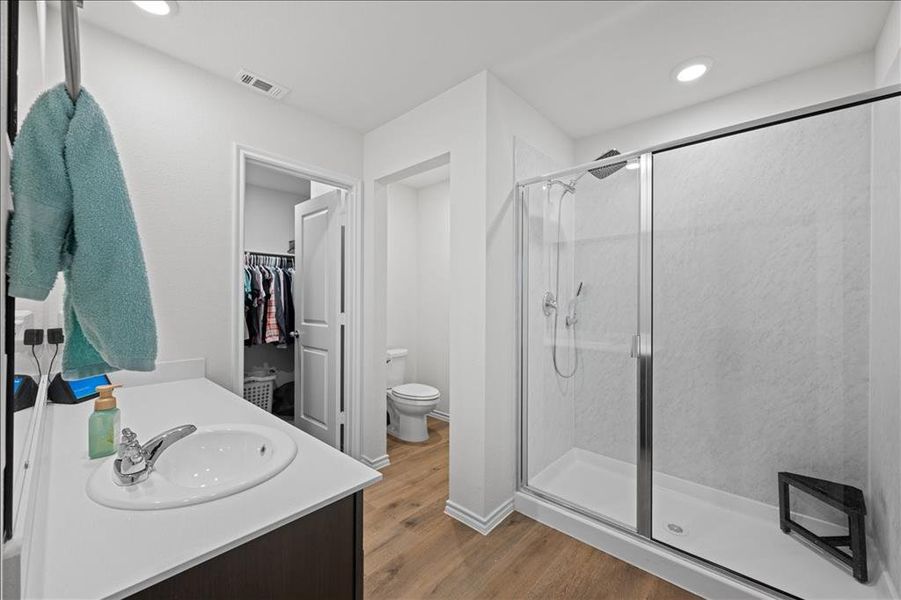 Full bathroom with light wood-type flooring, a walk in closet, a stall shower, vanity, and recessed lighting Full bathroom with light wood-type flooring, a walk in closet, a stall shower, vanity, and recessed lighting
