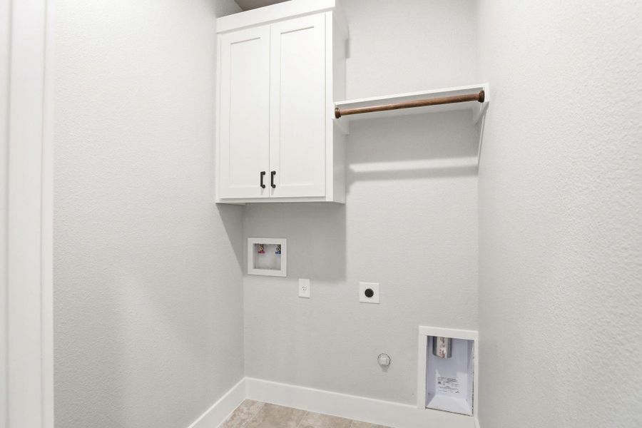 A dedicated laundry room with built-in cabinetry and a convenient clothing rod for drying. A dedicated laundry room with built-in cabinetry and a convenient clothing rod for drying.