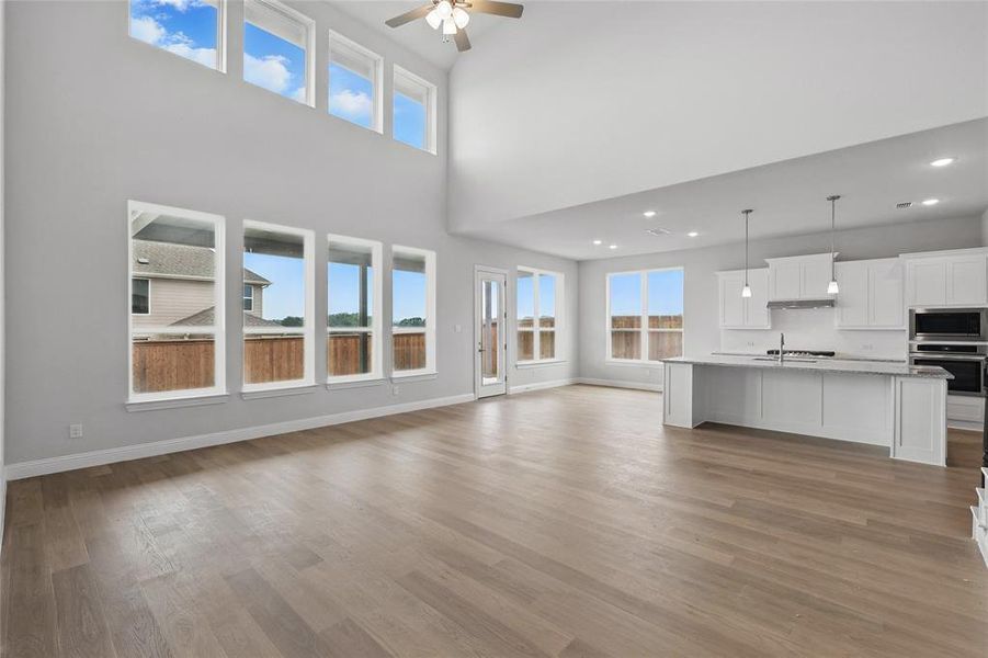 Unfurnished living room with ceiling fan, baseboards, light wood finished floors, recessed lighting, and a sink