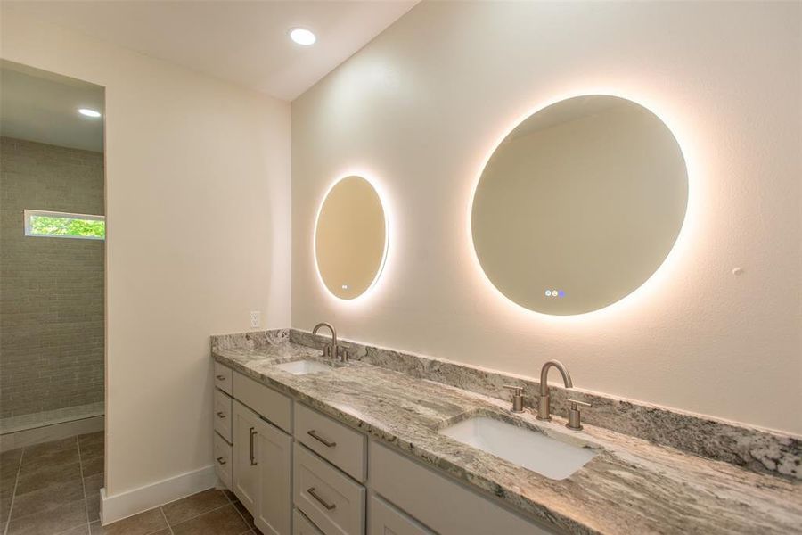 Bathroom with vanity, tiled shower, and tile patterned flooring