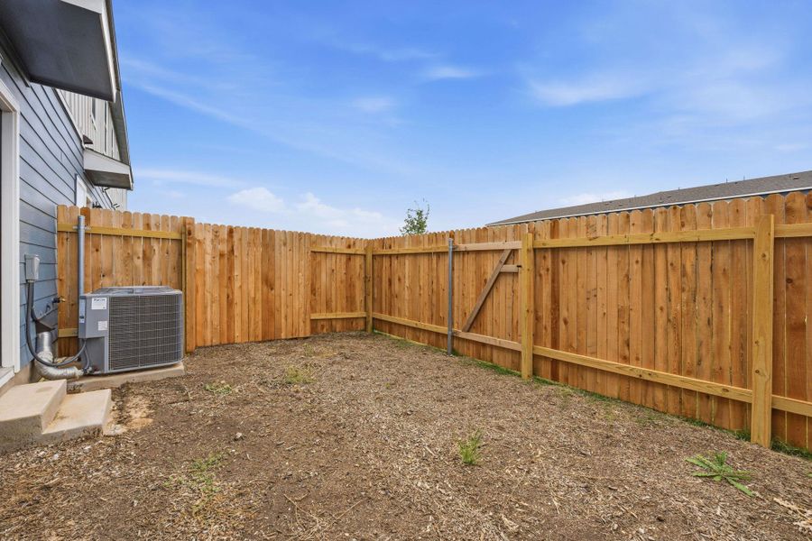 Enclosed backyard featuring a new wood fence and a side gate