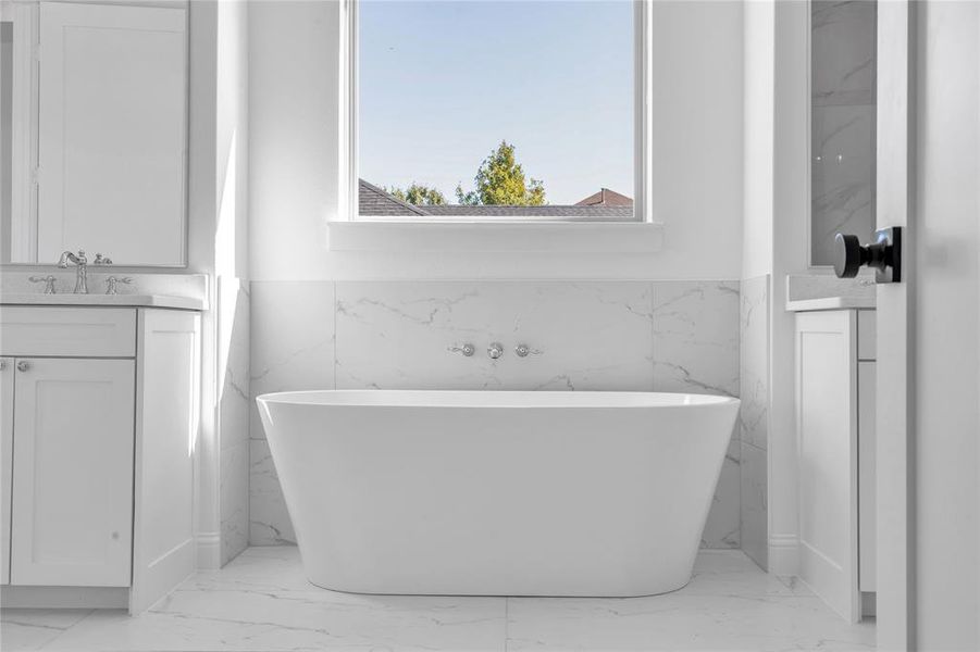 Full bath with vanity, light marble finish flooring, and a soaking tub