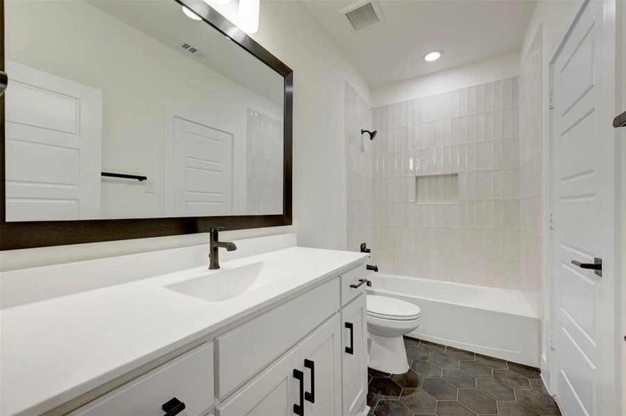 Full bathroom with vanity,  shower combination, and dark tile patterned floors