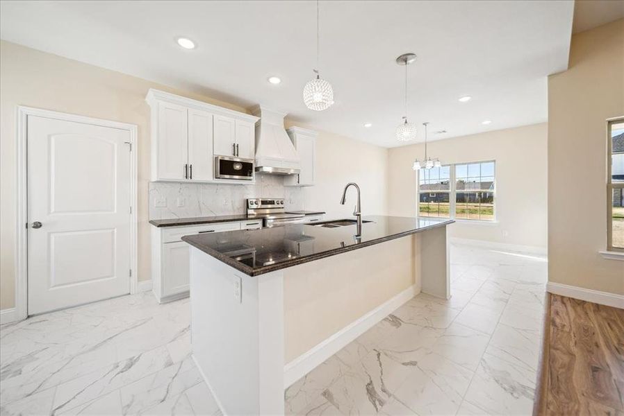 Kitchen featuring white cabinets, custom exhaust hood, sink, and stainless steel appliances