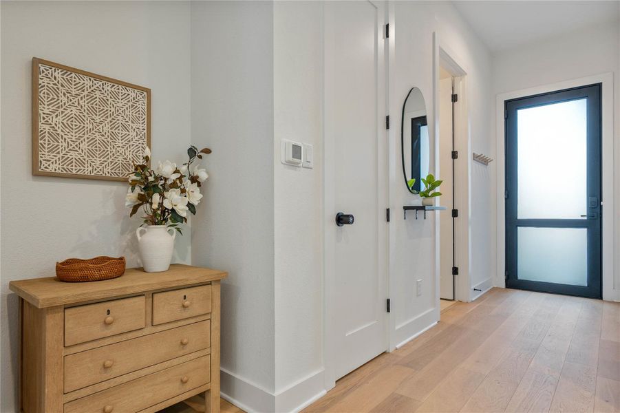 Smooth wood floors guide guests from the frosted glass entry door into the home.
