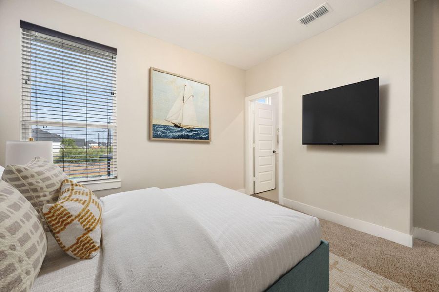 This secondary bedroom offers soft neutral tones, plush carpeting, and a large window that fills the space with natural light. A private en suite bath adds convenience, making this room ideal for guests or family members seeking comfort and privacy.