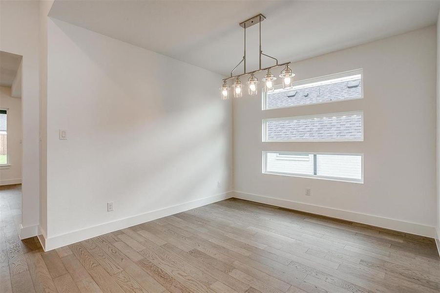 Unfurnished room featuring plenty of natural light, light hardwood / wood-style floors, and a notable chandelier