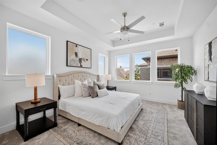Bedroom featuring a raised ceiling, carpet floors, and ceiling fan
