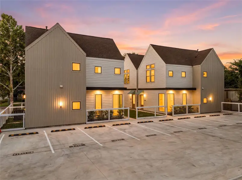 Stunning twilight view showcasing warm exterior accent lighting and open parking spaces. Stunning twilight view showcasing warm exterior accent lighting and open parking spaces.