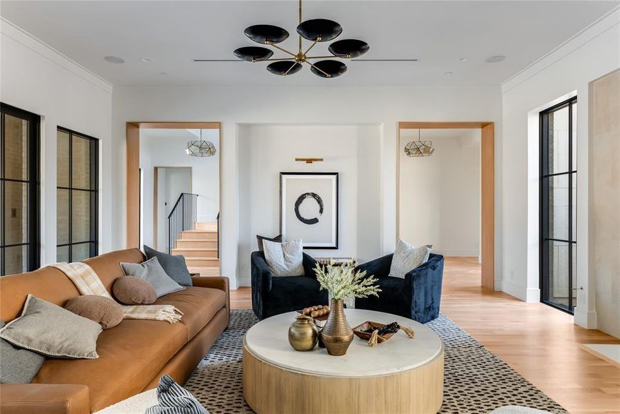 Living room featuring ornamental molding, light wood-type flooring, and an inviting chandelier