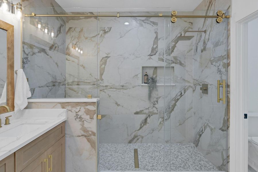 Stunning walk-in shower with floor-to-ceiling porcelain tile, frameless glass enclosure, built-in seating area, and a convenient soap alcove for added functionality. Stunning walk-in shower with floor-to-ceiling porcelain tile, frameless glass enclosure, built-in seating area, and a convenient soap alcove for added functionality.