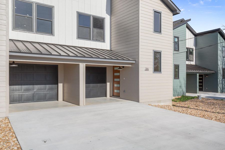 View of front facade featuring an attached garage, driveway, a standing seam roof, and board and batten siding