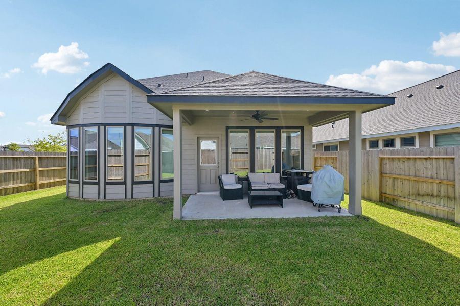 Charming backyard with a covered patio perfect for relaxation, featuring cozy outdoor seating and a well-maintained lawn.