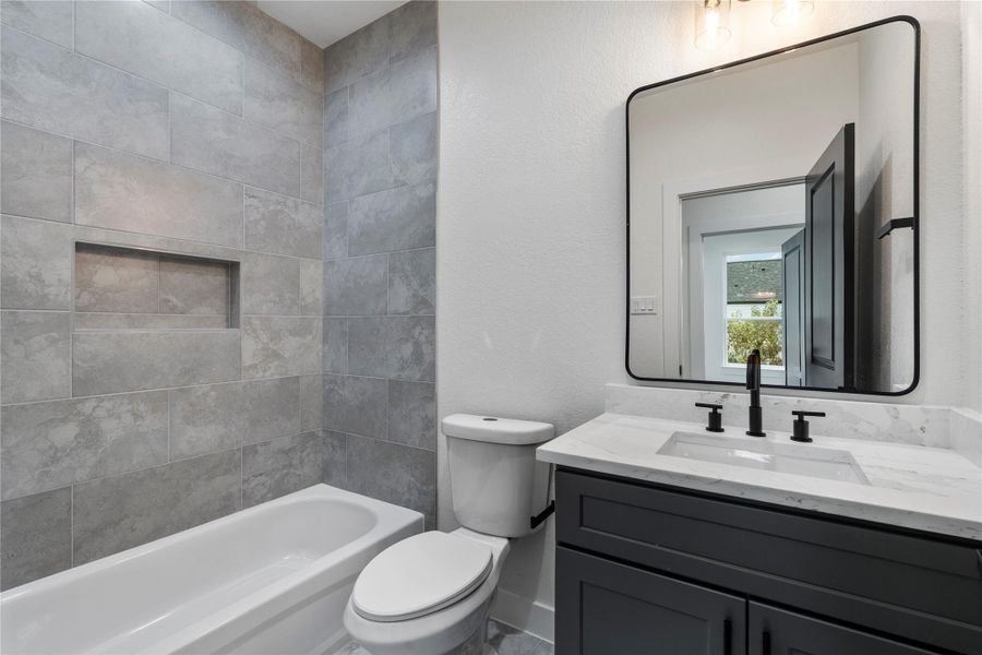 Third full bath with quartz vanity, modern fixtures, and textured tile surround. Third full bath with quartz vanity, modern fixtures, and textured tile surround.