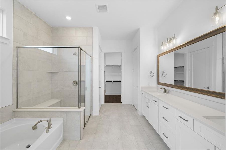 Spacious bathroom featuring a glass-enclosed shower with tiled bench, a separate soaking tub, and a dual vanity with a large framed mirror