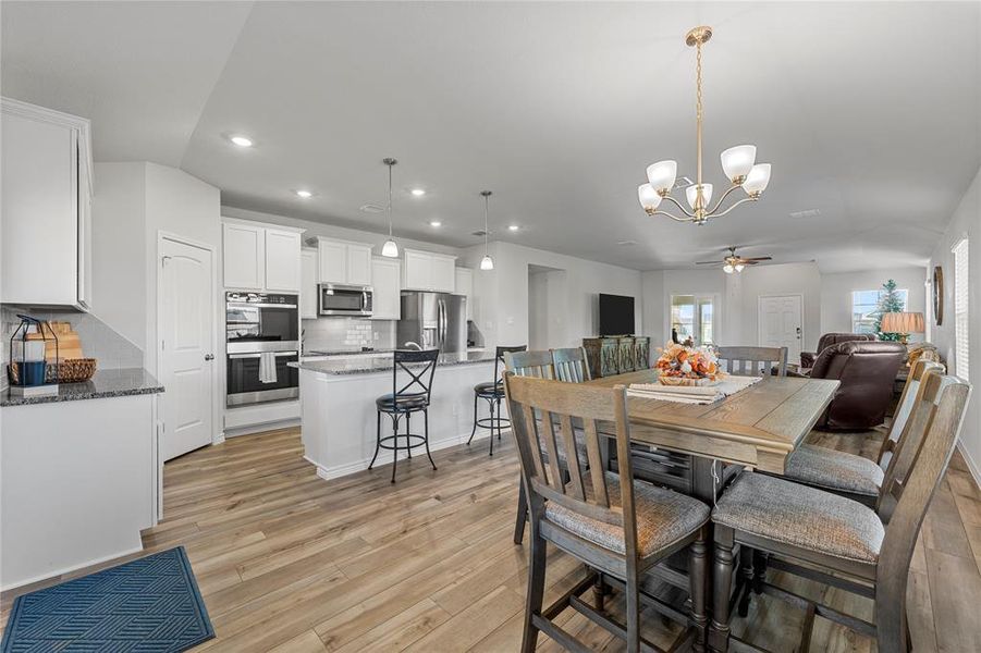 Dining space featuring a chandelier, light wood-type flooring, a ceiling fan, and recessed lighting