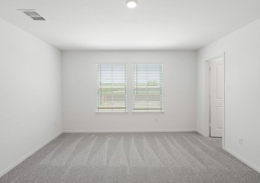 Master bedroom with lush carpet and a window