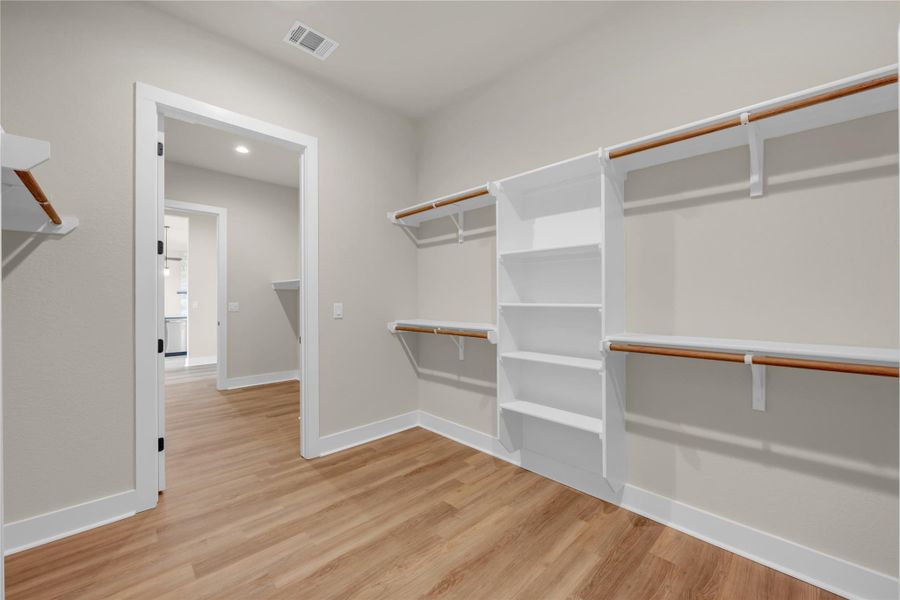 Walk in closet with light wood-flooring